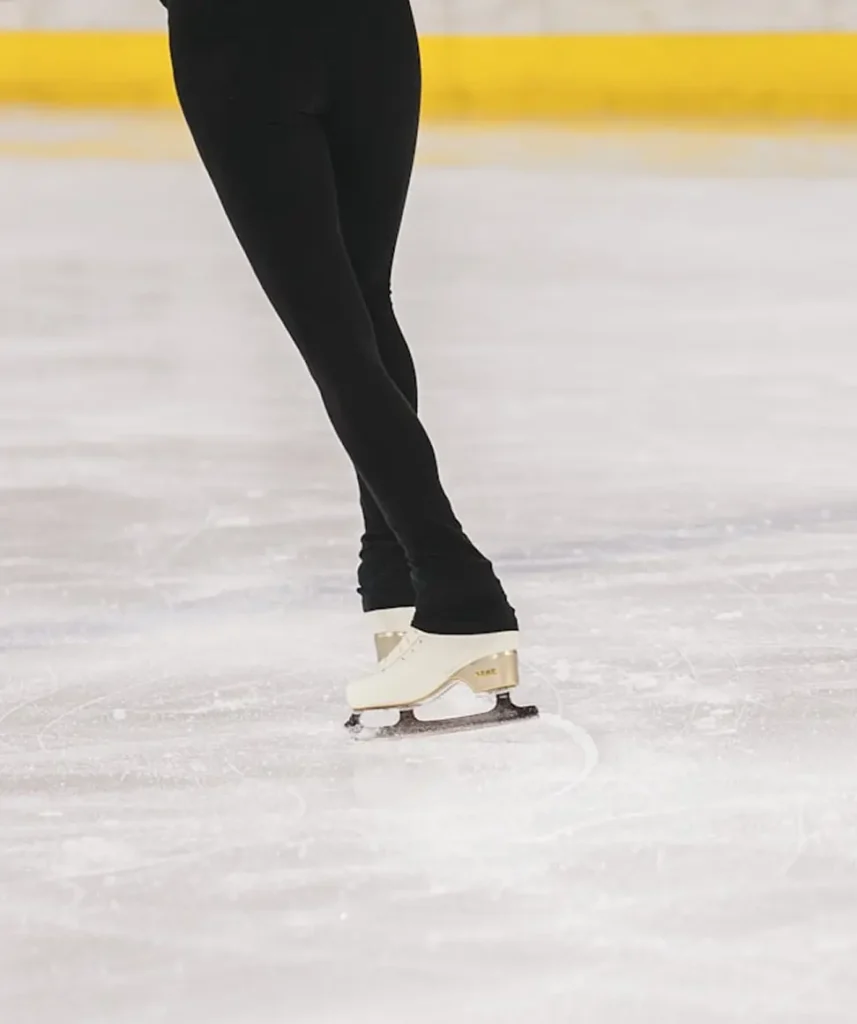Vi ser två ben av en konståkare ute på isen.