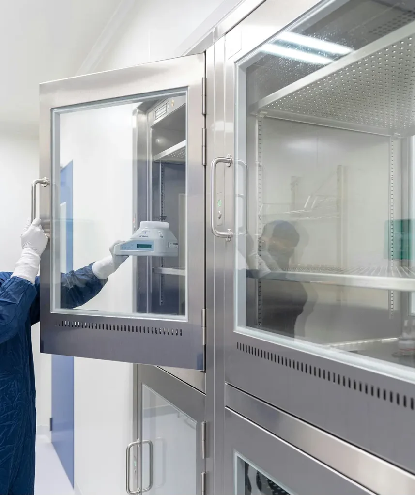 I ett laboratorie ser vi en person öppna ett kylskåp för attt lägga in ett objekt.