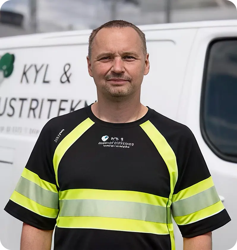 På bilden ser vi en manlig anställd iför arbetskläder ståendes framför sin arbetsbil.