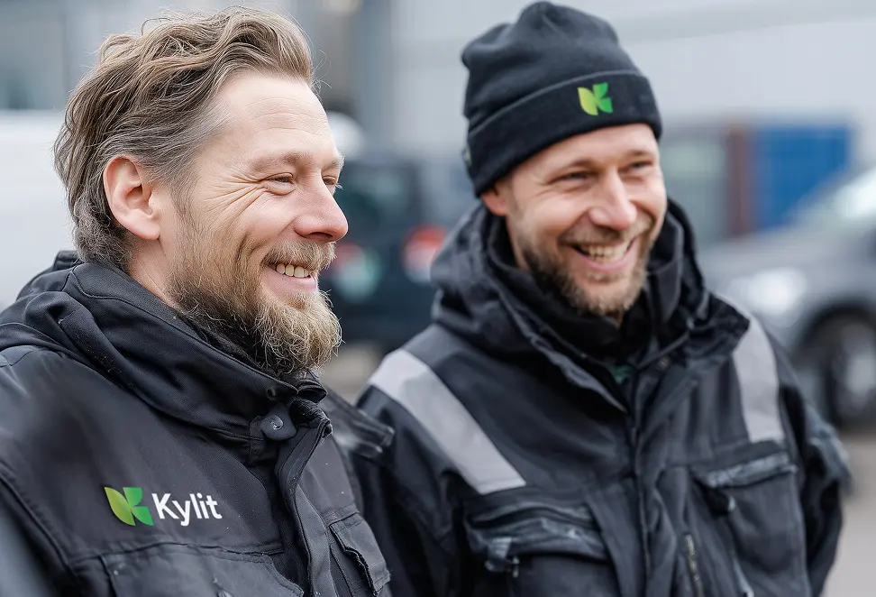 Två män som ler och har arbetskläder märkta av företaget Kylit.