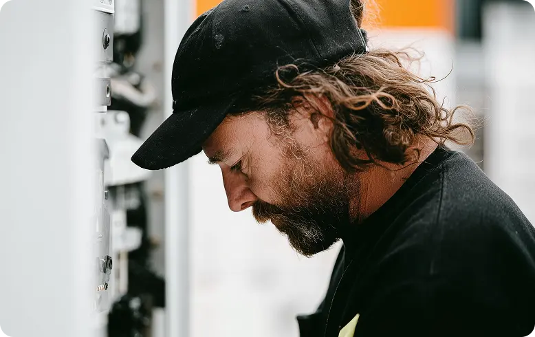 En kyltekniker i keps tittar ner på det projekt han är ute och jobbar på.